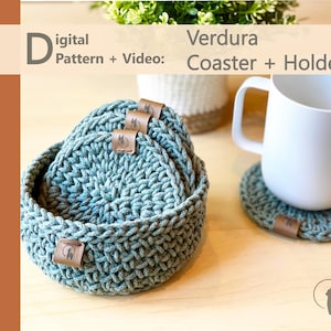 Puede incluir: Un juego de posavasos de ganchillo en color verde salvia y un soporte circular a juego, cada uno con una pequeña etiqueta de cuero marrón con un logo de llama. El texto Digital Pattern + Video: Verdura Coaster + Holder es visible arriba.