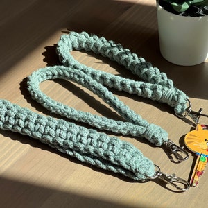 May include: Three crocheted keychains in a light green color with silver key rings. The keychains are made with a thick, textured yarn and have a simple, minimalist design.