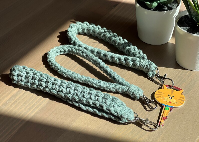 May include: Three crocheted keychains in a light green color with silver key rings. The keychains are made with a thick, textured yarn and have a simple, minimalist design.