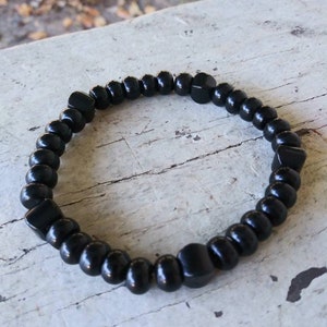 May include: A black beaded bracelet with square-shaped beads.