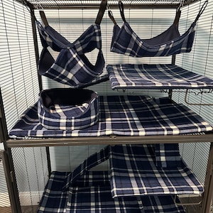 Puede incluir: Un conjunto de accesorios de tela a cuadros azul oscuro, blanco y azul claro para una jaula de alambre, que incluye dos hamacas colgantes, una cama circular, una alfombrilla rectangular y una cubierta de rampa. El texto en la parte inferior dice: This is an example photo. Please see Item Details Section for more information.