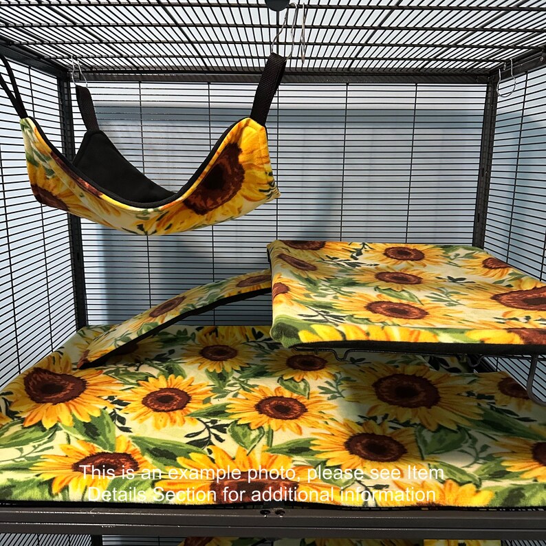 Puede incluir: Un conjunto de accesorios para jaulas de animales peque&ntilde;os con estampado de girasoles sobre fondo crema. Incluye una hamaca colgante con interior negro, una funda para plataforma rectangular y una funda para rampa de tela suave con girasoles.