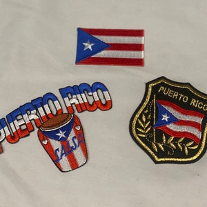 Può includere: Tre toppe ricamate con la bandiera di Porto Rico. La prima toppa è un semplice disegno di bandiera. La seconda toppa è un marchio di parola che dice "PUERTO RICO" con un tamburo rosso e bianco con il disegno della bandiera e la parola "SALSA" su di esso. La terza toppa è uno scudo con il disegno della bandiera e le parole "PUERTO RICO" su di esso.