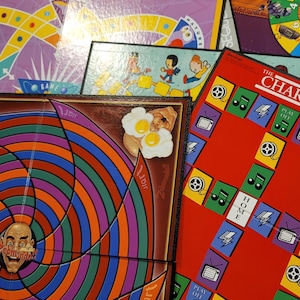 May include: A collection of vintage board games, including a red and blue game board with the words "Play Off" and "Home", a brown game board with a colorful spiral and the word "Zobmondo!!", and a purple game board with a yellow and orange path.