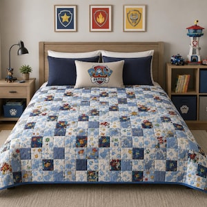 May include: A blue and white patchwork quilt with a Paw Patrol theme, featuring character images and paw prints. The bed is made with navy blue pillows and a decorative pillow with the Paw Patrol logo. The room includes a wooden nightstand and a storage unit.