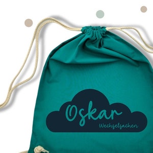 Peut inclure: Sac à cordon turquoise avec un motif de nuage blanc et le texte "Oskar Wechsel Sachen".