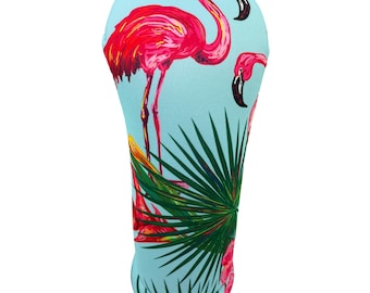 May include: A golf club head cover featuring a vibrant design of pink flamingos and green palm fronds against a light blue background. The cover is shaped to fit a golf club and provides protection. The flamingo's long legs and curved necks are prominent.