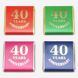 May include: Four chocolate bars with gold foil wrappers. Each bar has a different colour: red, green, pink, and blue. The bars all have the same design: "40 Years Anniversary" in gold lettering.