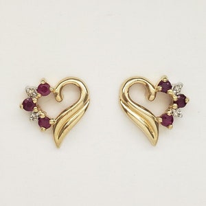 May include: A pair of gold heart-shaped earrings with red and white gemstones.