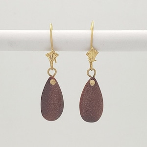 May include: A pair of brown teardrop-shaped earrings with gold hooks.