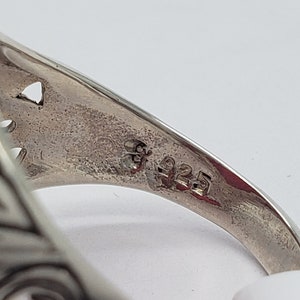 May include: Close-up of the inside of a silver ring with an ornate design. The ring is marked with "925", indicating it is made of sterling silver.