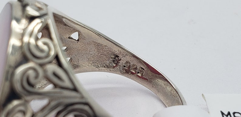 May include: Close-up of the inside of a silver ring with an ornate design. The ring is marked with "925", indicating it is made of sterling silver.