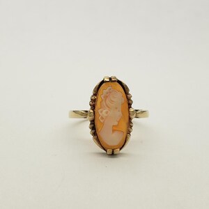 May include: A gold ring with a cameo of a woman's profile set in a oval shaped frame.