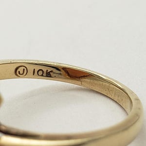 May include: A gold ring with a carved orange stone. The ring is marked "10K" on the inside band.