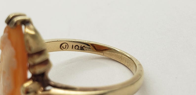 May include: A gold ring with a carved orange stone. The ring is marked "10K" on the inside band.
