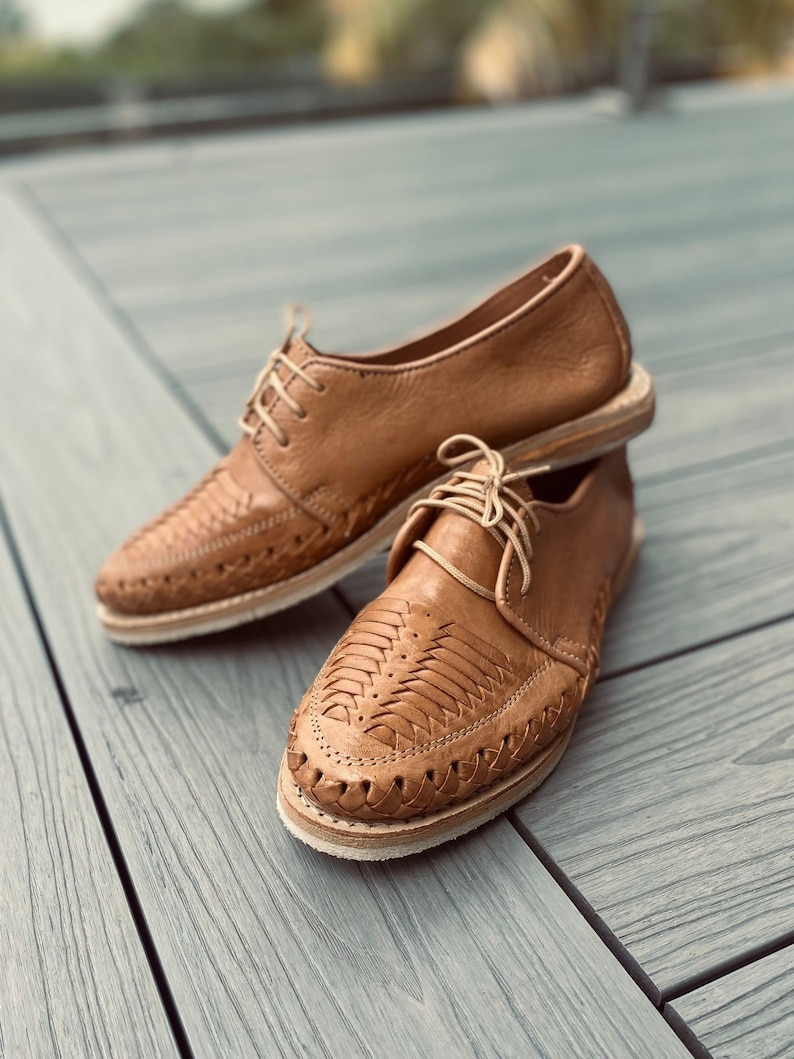 May include: A pair of brown leather shoes with intricate woven designs. The shoes have a lace-up closure and a pointed toe.