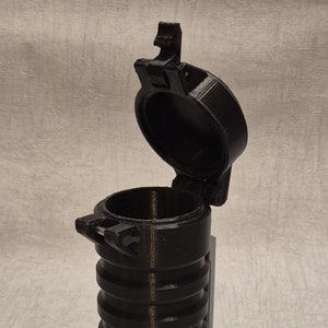 May include: A black plastic container with a hinged lid. The container has a ribbed design and is open.