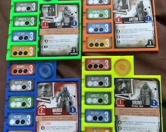 May include: Four colorful game boards with character cards for a board game. Each board has a character card with a photo of a person, a name, and a description. The boards have different colored borders and are labeled with categories like "Wounds", "Misery", "Hunger", "Fatigue", and "Illness".