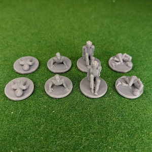 May include: Eight gray plastic miniature figures on round bases. The figures are in various poses, including sitting, standing, and lying down.