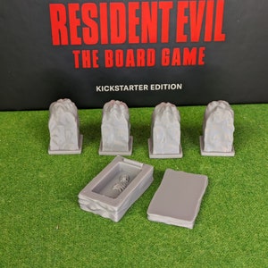 Könnte beinhalten: Fünf graue, steinartige Spielsteine und zwei graue rechteckige Spielsteine aus der Resident Evil: The Board Game Kickstarter Edition.