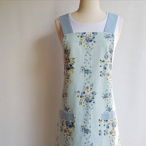 May include: A light blue apron with a floral print and blue straps. The apron has two pockets on the front.