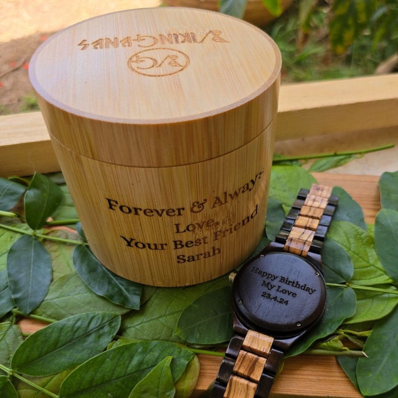 May include: A wooden watch with a black face and a brown and black wood band. The watch face has the text "Happy Birthday My Love 23.4.24" engraved on it. The watch is in a wooden box with the text "Forever & Always Love Your Best Friend Sarah" engraved on it.
