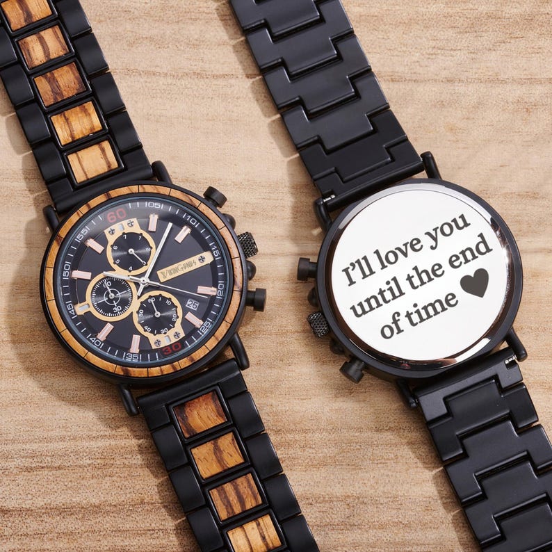 Puede incluir: Dos relojes negros con detalles de madera y dorados. Una esfera muestra m&uacute;ltiples diales y la otra tiene el texto "I'll love you until the end of time" con un s&iacute;mbolo de coraz&oacute;n. Las correas son negras.