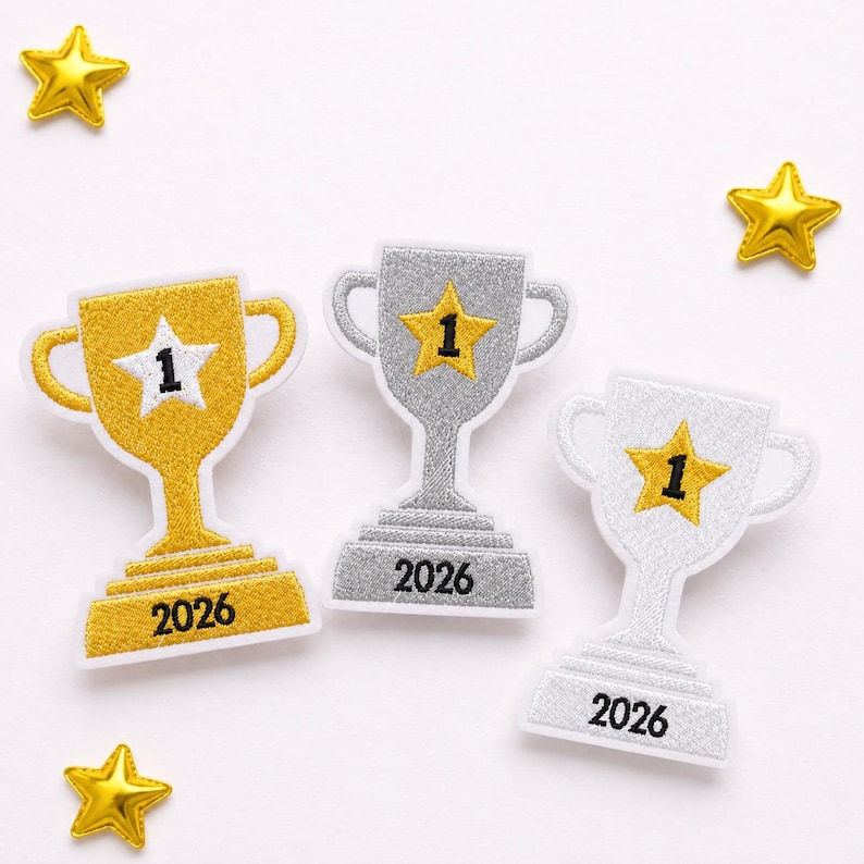 May include: Three embroidered trophy patches with white borders. One gold trophy features a white star with the number 1 and the year 2026. Two silver trophies feature yellow stars with the number 1 and the year 2026. Two small gold star accents are included.