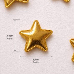 May include: A metallic gold star-shaped applique with a textured surface. The star features a stitched border detail. Technical markings indicate a height of 3.4 cm and a width of 3.6 cm, providing precise measurements for this decorative item.