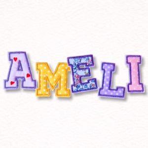 Könnte beinhalten: Bunte Stoffbuchstaben mit der Aufschrift "AMELI". Die Buchstaben sind in verschiedenen Farben und Mustern gehalten, darunter Lila mit Herzen, Gelb mit weißen Punkten, Blumendruck und Lila mit Tupfen. Ideal zum Basteln oder Dekorieren.