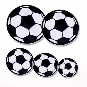 Könnte beinhalten: Ein Set aus fünf runden gestickten Aufnähern mit einem klassischen schwarz-weißen Fußballmuster. Die Aufnäher variieren in der Größe, mit zwei größeren oben und drei kleineren in einer Reihe darunter, alle mit sauber vernähten Rändern.