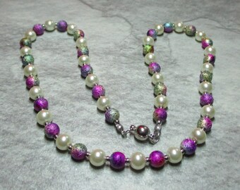 May include: A white pearl necklace with iridescent purple and green beads. The necklace has a magnetic clasp.
