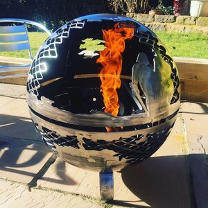 May include: A metal globe fire pit with a world map design. The fire pit is burning with orange flames.