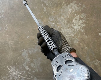May include: A metal Predator skull fire poker with a long handle. The handle has the word "PREDATOR" engraved on it.