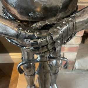 Op de afbeelding: Een zilveren metalen ridderbeeld met een zwaard in zijn hand. De ridder draagt ​​een harnas en heeft een gedetailleerd ontwerp.
