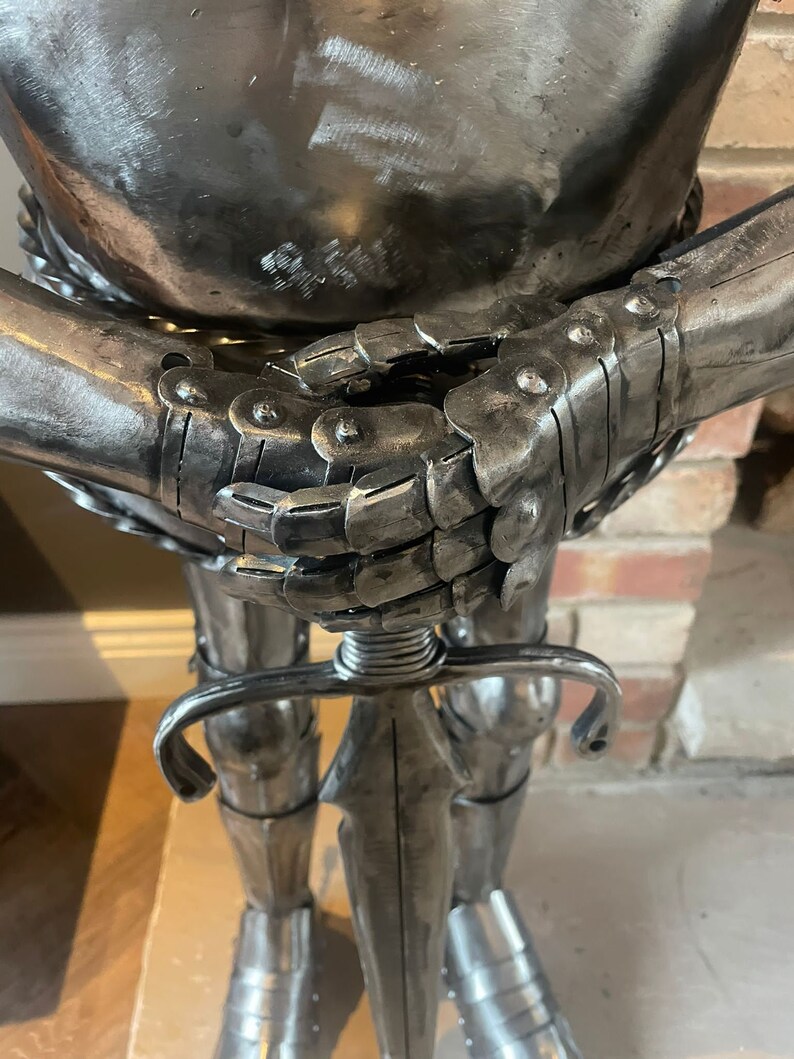 Op de afbeelding: Een zilveren metalen ridderbeeld met een zwaard in zijn hand. De ridder draagt ​​een harnas en heeft een gedetailleerd ontwerp.