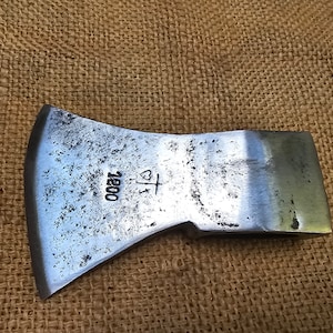 May include: A silver axe head with a wooden handle. The axe head has a heart and cross symbol and the number 1200 stamped on it.