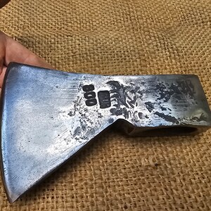 以下が含まれることがあります： 鋼製の仕上げが施されたビンテージの斧の頭。斧の頭には側面に「800」という刻印があります。