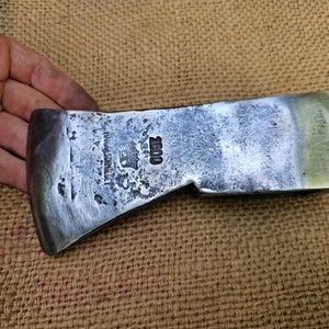 May include: A vintage, silver-colored axe head with a wooden handle. The axe head has the text "HANS SCHNEIDER" and "2500" stamped on it.