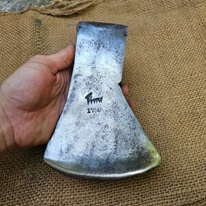 Könnte beinhalten: Ein antiker Axtkopf mit silberner Oberfläche und einer schwarzen Inschrift mit der Aufschrift "Flinn 1750".