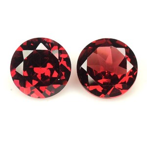 May include: Two round, red gemstones with a faceted cut. The gemstones are set against a white background.