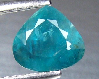May include: A teal blue gemstone with a pear-shaped cut. The gemstone is faceted and has a high degree of brilliance.