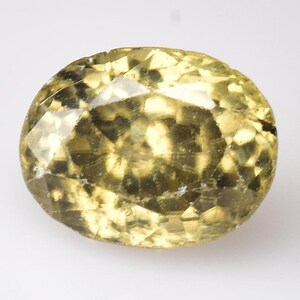 Puede incluir: Una gema facetada de forma ovalada con un tono amarillo pálido. La gema tiene múltiples facetas que reflejan la luz, creando un efecto brillante. La piedra está sobre un fondo blanco.