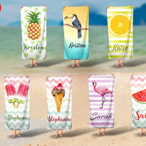 May include: Beach towels with various designs, including a pineapple, toucan, lemon slice, popsicles, ice cream cone, flamingo, and watermelon. Each towel features a name in script font. The towels are held up on a sandy beach.