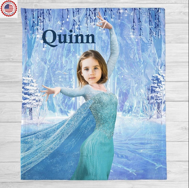 May include: A personalized blue blanket featuring a young girl in a teal dress, set against a winter wonderland backdrop. The name "Quinn" is displayed in large, dark blue letters at the top. The blanket has a soft, plush appearance.