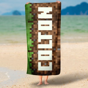 May include: A beach towel with a Minecraft-inspired design featuring a brown and green pixelated background and the name "Colton" in white pixelated letters.