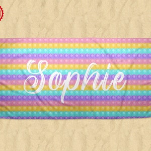 May include: A colorful beach towel with a rainbow pop-it design and the name "Sophie" written in white.