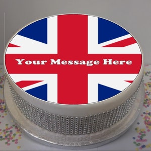 May include: A white cake decorated with an edible image of the Union Jack flag. The cake is surrounded by silver glitter and the text "Your Message Here" is printed on the flag.