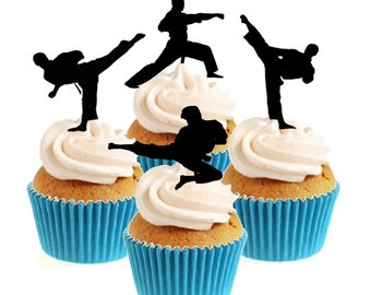 May include: Four cupcakes with blue liners and white frosting. Each cupcake is topped with a black silhouette of a person in a karate pose.