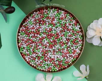 May include: A bowl of green, red, and silver sprinkles. The sprinkles are in a gold bowl and are on a green and white background. The text "Sprinkles & Toppers LTD" is printed on the top of the image.